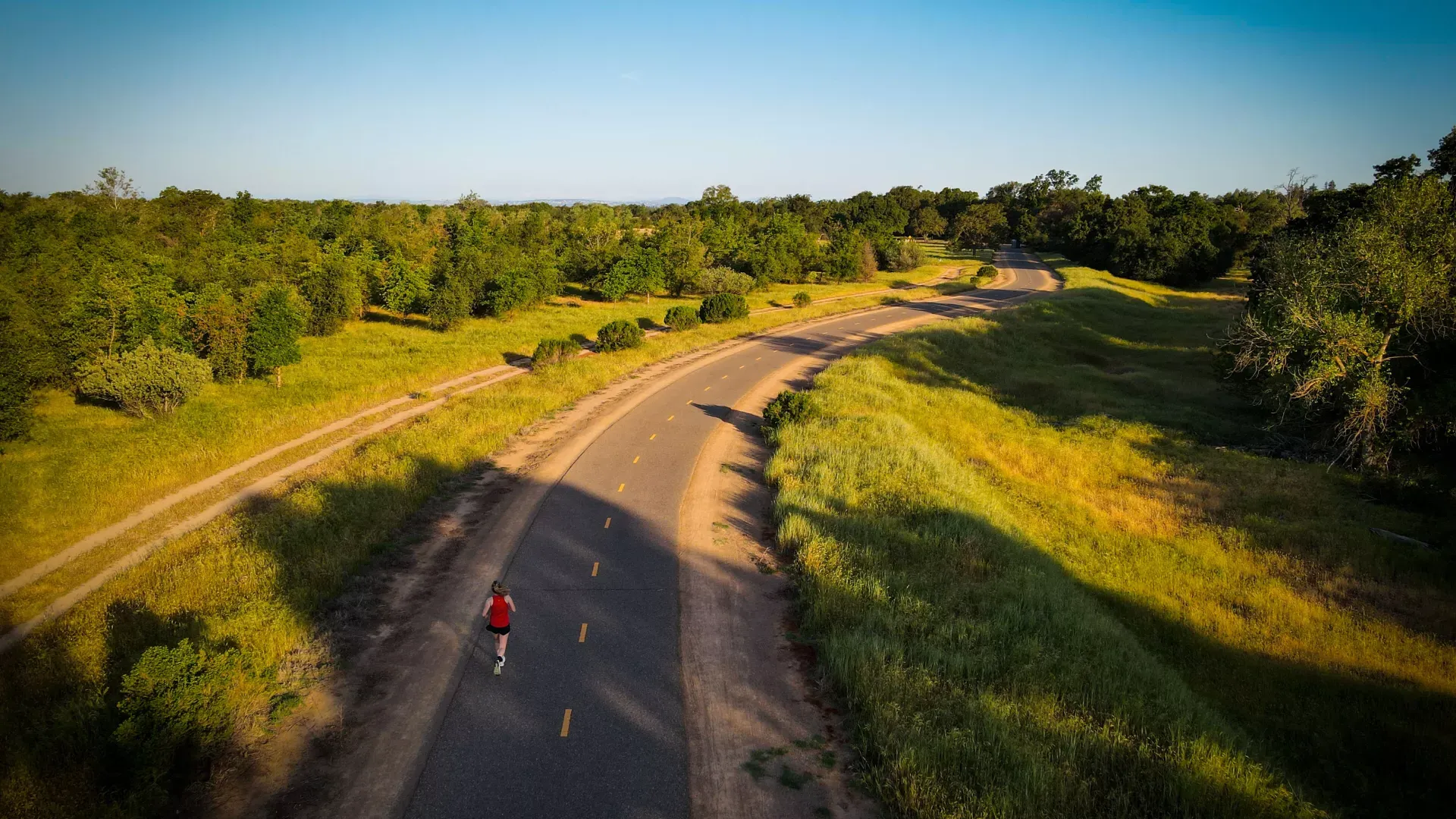 Overhead shot of woman running on a road through the countryside